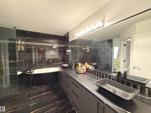 Bathroom featuring full-height black and gold veined tile, a freestanding soaking tub, and a glass-enclosed shower - 1210 Peregrine Terrace, Edmonton, AB - Indoor Photo Showing Bathroom