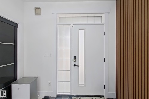 Entryway featuring a white door with a vertical frosted glass insert, an adjacent frosted sidelight with grid details, and a transom window above - 1210 Peregrine Terrace, Edmonton, AB - Indoor Photo Showing Other Room