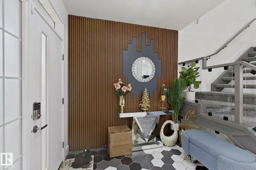 Entryway featuring a wood slat accent wall, hexagonal tile flooring, and a glass-paneled staircase with carpeted treads - 1210 Peregrine Terrace, Edmonton, AB - Indoor Photo Showing Other Room