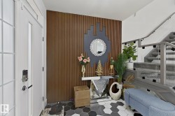 Entryway featuring a wood slat accent wall, hexagonal tile flooring, and a glass-paneled staircase with carpeted treads - 