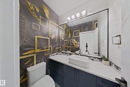 Powder room featuring a large rectangular mirror, vessel sink, and a blue base vanity with a white countertop - 1210 Peregrine Terrace, Edmonton, AB - Indoor Photo Showing Bathroom