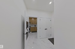 Bright hallway with white walls, recessed lighting, and large format marble-look tile flooring - 