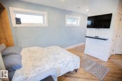 Wood-finish flooring throughout this room featuring a mounted flat-screen television with a floating shelf below - 