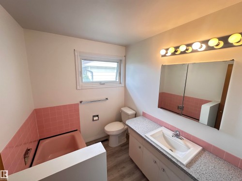 Bathroom featuring a vanity with an integrated sink, speckled countertop, and under-cabinet storage - 11131 52 Street, Edmonton, AB - Indoor Photo Showing Bathroom