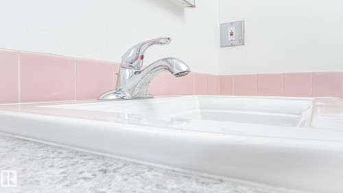 White ceramic sink with a chrome faucet, set against a countertop with a subtle textured finish - 11131 52 Street, Edmonton, AB - Indoor Photo Showing Bathroom