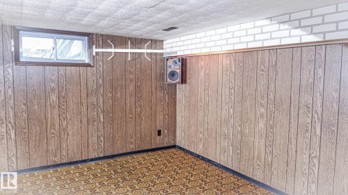 Recreation room featuring wood paneling, white brick accent, geometric pattern carpet, and acoustic ceiling tiles - 11131 52 Street, Edmonton, AB - Indoor Photo Showing Other Room