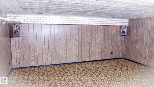 Recreation room featuring wood paneling, white brick accent, geometric pattern carpet, and acoustic ceiling tiles - 11131 52 Street, Edmonton, AB -  Photo Showing Other Room