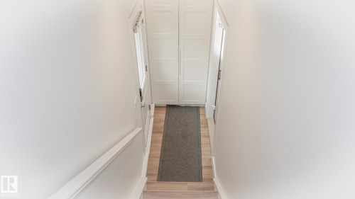 Well-lit hallway featuring light wood-finish flooring, white walls, and a white handrail - 11131 52 Street, Edmonton, AB - Indoor Photo Showing Other Room