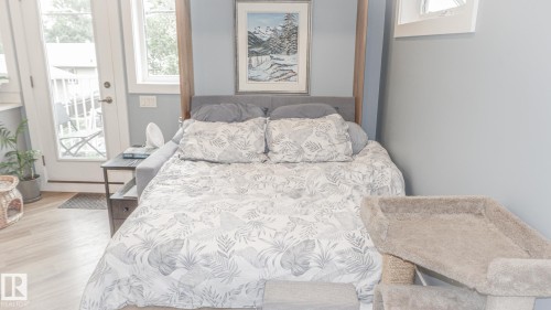 Room featuring light wood-finish flooring and a built-in wall bed with a gray upholstered headboard - 11131 52 Street, Edmonton, AB - Indoor Photo Showing Bedroom