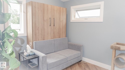 Room featuring a light wood-finish wall unit, two windows with white trim, and light blue wall paint - 11131 52 Street, Edmonton, AB - Indoor