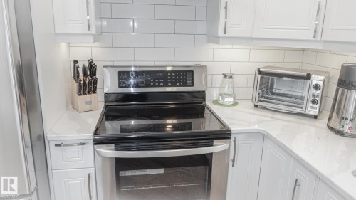 Stainless steel range with a flat cooktop, complemented by white subway tile backsplash - 11131 52 Street, Edmonton, AB - Indoor Photo Showing Kitchen