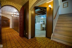Arched brickwork accents a hallway featuring patterned carpet flooring and wood-paneled walls - 