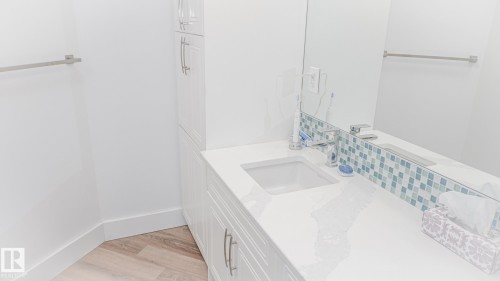 White vanity with integrated sink, contemporary faucet, and a blue and white mosaic tile backsplash - 11131 52 Street, Edmonton, AB - Indoor Photo Showing Bathroom