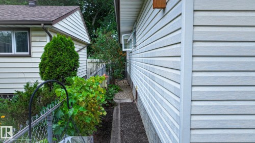 Light-colored horizontal siding facade with a window and foundation stonework - 11131 52 Street, Edmonton, AB - Outdoor With Exterior