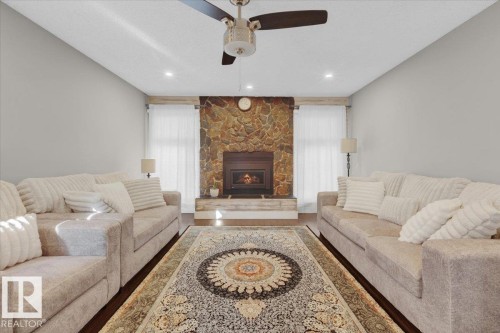 Living area with a stone fireplace, wood finished floors, recessed lighting, and ceiling fan - 3515 20 Avenue, Edmonton, AB - Indoor Photo Showing Living Room With Fireplace