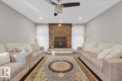 Living area with a stone fireplace, wood finished floors, recessed lighting, and ceiling fan - 