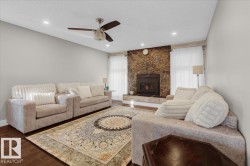 Living room featuring a fireplace, wood finished floors, a textured ceiling, a ceiling fan, and recessed lighting - 