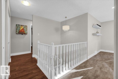 Hallway featuring an upstairs landing, a textured ceiling, and dark wood-style flooring - 3515 20 Avenue, Edmonton, AB - Indoor Photo Showing Other Room