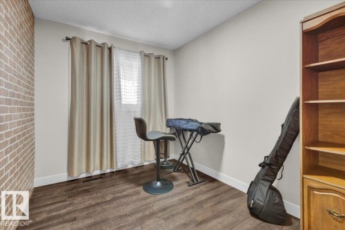 Unfurnished room featuring a textured ceiling, dark wood finished floors, and brick wall - 3515 20 Avenue, Edmonton, AB - Indoor Photo Showing Other Room