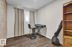 Unfurnished room featuring a textured ceiling, dark wood finished floors, and brick wall - 