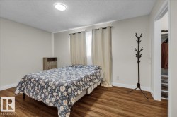 Bedroom with a textured ceiling and dark wood finished floors - 