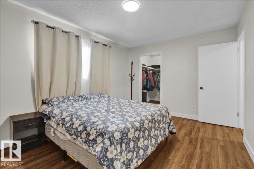 Bedroom with a textured ceiling, wood finished floors, and a walk in closet - 3515 20 Avenue, Edmonton, AB - Indoor Photo Showing Bedroom