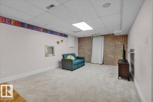 Unfurnished room featuring brick wall, a paneled ceiling, and carpet flooring - 3515 20 Avenue, Edmonton, AB - Indoor