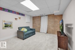 Living area featuring brick wall, carpet flooring, and a paneled ceiling - 