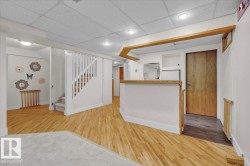 Interior space with a drop ceiling, wood finished floors, stairway, and recessed lighting - 