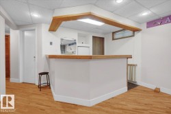Bar with a paneled ceiling and light wood-style floors - 