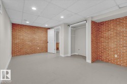Unfurnished bedroom with brick wall, finished concrete flooring, and a paneled ceiling - 