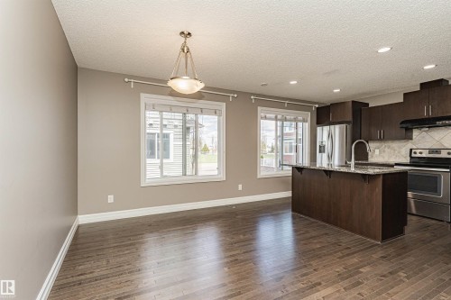 Open-concept living area featuring wood-finish flooring and ample natural light from two windows - 110 3625 144 Avenue, Edmonton, AB - Indoor Photo Showing Kitchen