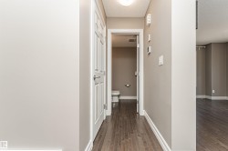 Hallway featuring wood-finish flooring, white trim, and a built-in overhead light fixture - 