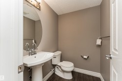 Pedestal sink with chrome fixtures, oval mirror, and wall-mounted light fixture - 