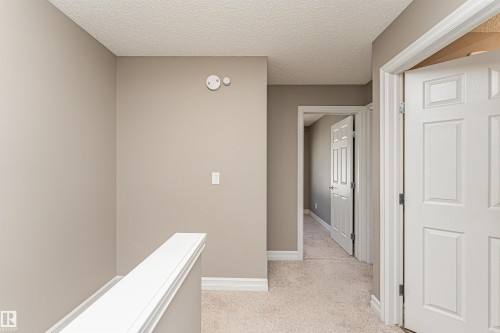 Carpeted hallway with neutral wall tones and white trim - 110 3625 144 Avenue, Edmonton, AB - Indoor Photo Showing Other Room