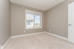 Bedroom space featuring a window with white trim, neutral wall paint, light-colored carpet, and white baseboards - 