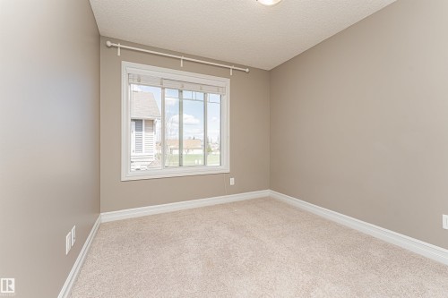 Room featuring a large white-framed window, neutral-toned walls, and plush carpet flooring - 110 3625 144 Avenue, Edmonton, AB - Indoor Photo Showing Other Room