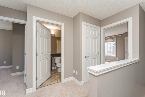 Carpeted hallway featuring a neutral color palette, white trim, and doors with brushed chrome hardware - 110 3625 144 Avenue, Edmonton, AB - Indoor Photo Showing Other Room