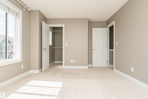 Neutral tone wall paint with white trim, soft carpet flooring, and a window with roller blinds - 110 3625 144 Avenue, Edmonton, AB - Indoor Photo Showing Other Room