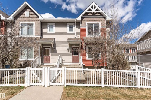 Contemporary townhome exterior featuring multi-toned siding, stone accents, and a front entry with white railing and gate - 110 3625 144 Avenue, Edmonton, AB - Outdoor With Facade