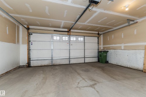 Two-car garage featuring a concrete floor, automatic garage door opener, and integrated windows on the garage door - 110 3625 144 Avenue, Edmonton, AB - Indoor Photo Showing Garage