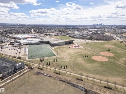 Aerial perspective showcasing a large sports complex with an artificial turf field, multiple baseball diamonds, and a recreational park area - 