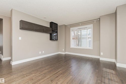 Spacious interior room featuring wood-finish flooring, light neutral wall tones, and white baseboards - 110 3625 144 Avenue, Edmonton, AB - Indoor Photo Showing Other Room