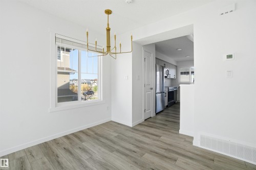 Dining area featuring wood-finish flooring and a contemporary gold chandelier - 64 17832 78 Street, Edmonton, AB - Indoor Photo Showing Other Room