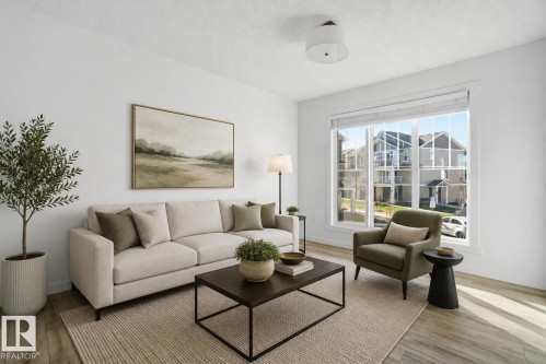 Bright living area featuring wood-finish flooring and a large picture window with white trim - 64 17832 78 Street, Edmonton, AB - Indoor Photo Showing Living Room