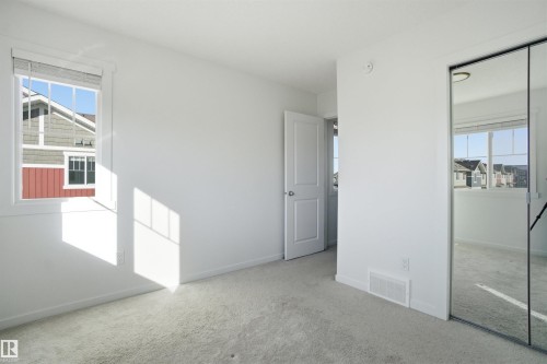 Bright room featuring a window with white blinds, light-colored carpeting, and a mirrored closet door - 64 17832 78 Street, Edmonton, AB - Indoor Photo Showing Other Room