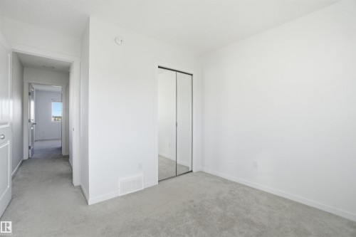 Light grey carpeted room featuring a mirrored bi-fold closet and white trim - 64 17832 78 Street, Edmonton, AB - Indoor Photo Showing Other Room