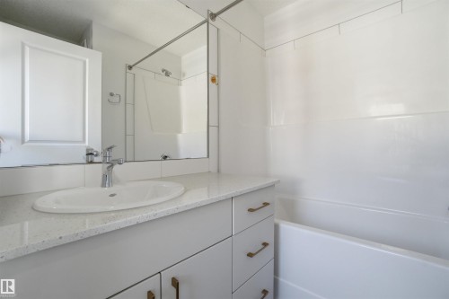 Bathroom featuring a vanity with an integrated sink, a speckled countertop, and brushed brass hardware - 64 17832 78 Street, Edmonton, AB - Indoor Photo Showing Bathroom