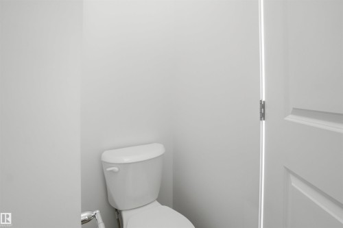 White porcelain toilet with a chrome toilet paper holder - 64 17832 78 Street, Edmonton, AB - Indoor Photo Showing Bathroom