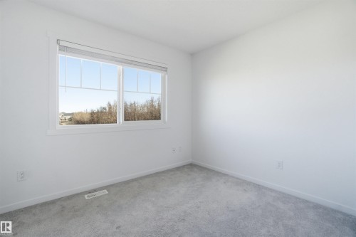Bright room featuring a large window, light gray carpet, white walls, white trim, and a white ceiling - 64 17832 78 Street, Edmonton, AB - Indoor Photo Showing Other Room